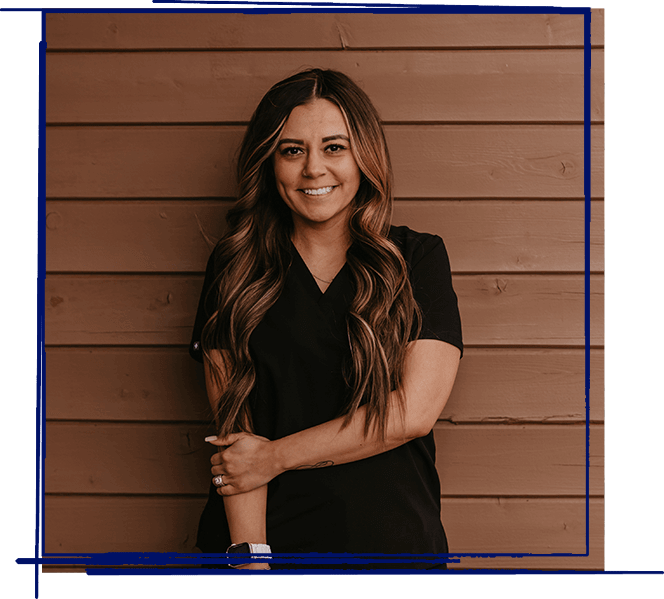 Woman smiling at camera wearing black shirt against wooden wall backdrop.