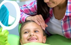 Pediatric dentist examining young child's teeth during dental checkup at clinic.